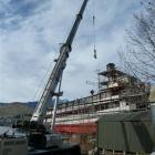 A crane lifts one of the main engine crankshafts through the roof of the TSS Earnslaw last week...