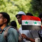 A demonstrator holds the Syrian flag during a protest in New Delhi, India, against potential US...