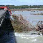 A digger attempts to clear trees hit by two trucks early yesterday after they were washed by...