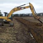 A digger lays the first pipe in an extension to the North Otago Irrigation Company's scheme,  on...