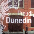 A Dunedin Heritage Fund sign in a dusty old window  in Vogel St reflects the beautifully restored...