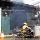 A fireman works at the scene of a shed fire in Exe St yesterday. Photo by Sally Rae.