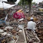 A flood-affected man sits over debris of his house collapsed by flooding in Nowshera, northwest...