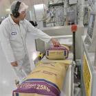 A Fonterra Studholme plant worker watches bags of  milk powder roll off the line. Photo by Fonterra.