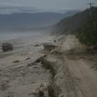 A four-wheel drive vehicle makes its way along Blue cliffs Beach, next to the washed out...