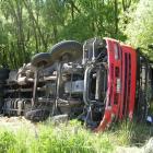 A furniture truck lies on its side down a bank near Tarras yesterday. Photo by Rosie Manins.