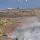 A helicopter crew douses flames on the Bannockburn side of Cornish Point yesterday.