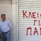 A hotel worker stands next to the shutter of a closed hotel during a protest against cutbacks and...