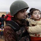 A Jordanian soldier carries a child belonging to a group of refugees who had crossed into Jordan...