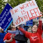 A Labour Party supporter holds her sign in front of a National Party supporter as the two groups...