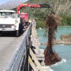 A log hoist is used to lift debris from around piers supporting the north bridge on State Highway...