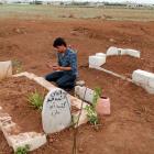 A man prays at the grave of a Free Syrian Army fighter at a cemetery at al-Karak al-Sharqi in...