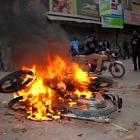 A man rides past motorbikes being burnt by supporters of Pakistan People's Party in Larkana to...