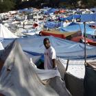 A man stands among tents made of bedsheets, tarps and sticks in a makeshift refugee camp in Port...
