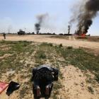 A member of militias known as Hashid Shaabi kneels as he celebrates victory while smoke rises...