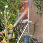 A member of the Wanaka Volunteer Fire Brigade hoses the flames inside a house in Beacon Point Rd,...