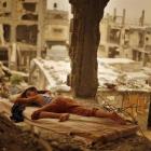 A Palestinian boy sleeps on a mattress inside the remains of his family's house, destroyed by...