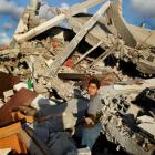 A Palestinian child gestures as he looks for belongings in the remains of his destroyed house in...