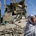 A Palestinian woman stands on the rubble of a destroyed building after an Israeli airstrike in...