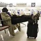 A passenger rests at Roissy Charles de Gaulle Airport, as hundreds of commercial flights across...