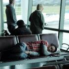 A passenger sleeps at Dunedin International Airport yesterday, with one of Air New Zealand's...