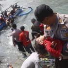 A police officer carries an unconscious child who was on a boat that capsized late off the coast...