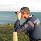 A police officer scans the coast for signs of life, during a search off the Oamaru coast...