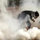 A protester against Egypt's President Mohamed Mursi tries to pick up a tear gas canister fired by...