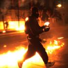 A protester runs with a petrol bomb towards riot police guarding the parliament in Athens'...