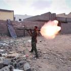 A revolutionary fighter fires a rocket-propelled grenade at Gaddafi loyalists in downtown Sirte,...