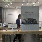 A shopkeeper dressed as an Apple store employee looks out from a window of a shop masquerading as...