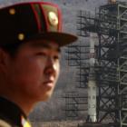 A soldier stands guard in front of the Unha-3 (Milky Way 3) rocket sitting on a launch pad at the...