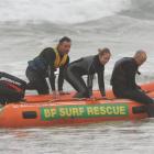 A stranded surfer (centre) is rescued from Bird Island yesterday by St Clair surf and rescue...