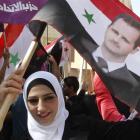 A supporter of Syria's President Bashar al-Assad waves a Syrian national flag depicting Assad's...