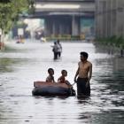 A Thai man pulls an improvised float to ferry children along flooded streets at the Lad Phrao...