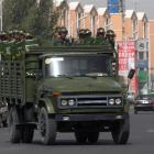 A truck carrying security personnel with anti-riot gear makes its ways through the street in Kuqa...