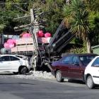 A truck which rolled backwards and damaged four cars, a van and a power pole sits against the...