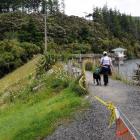 A walker and their dog enjoy a stroll along the top of the Ross Creek reservoir embankment in...