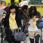 A woman reacts to a gust of wind outside Tokyo train station as a rainstorm batters Japan. (AP...