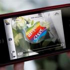 A woman uses her iPhone to take a photo of a sticker on a flower offered in memory of Apple co...