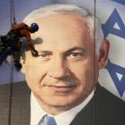 A worker installs a banner depicting Israel's Prime Minister Benjamin Netanyahu in Tel Aviv....