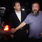 Activist artist Ai Weiwei, right, shakes hand with journalists outside his home in Beijing, China...