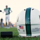 An American  football helmet's health warning sticker is pictured between a US flag and the...