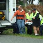 An injured motorcyclist is carried on a stretcher to an ambulance after crashing his machine...