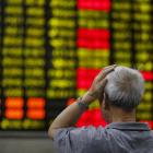 An investor looks at an electronic board showing stock information at a brokerage house in...