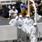 Armed Forces of Malta personnel  carry the body of a dead immigrant off Italian coastguard ship...