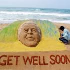 Artist Sudarshan Pattnaik works on a sand sculpture of former South African President Nelson...