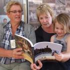 Barbara Newton (left), Sue Hore and Ruby Hore (3) look through Mrs Newton's book <i>Stonehenge...