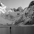 Bill Denz on a frozen Lake Marian, in Fiordland, with the mountain peak known as Sabre in the...