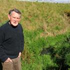 Blanket Bay resident Gerry Boyle stands beside a ditch where septic tank run-off has accumulated...